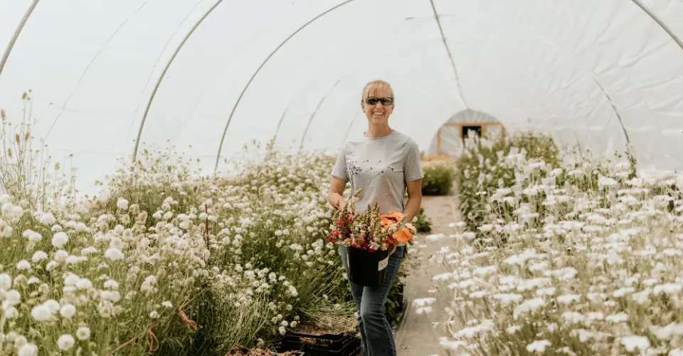 Liza, owner of Wildly Native Flower Farm, smiling in one of her hoop houses