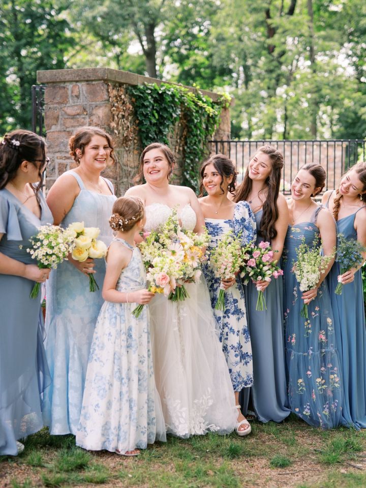 monofloral bridesmaids Bride and bridesmaids in blue smile, holding floral bouquets.