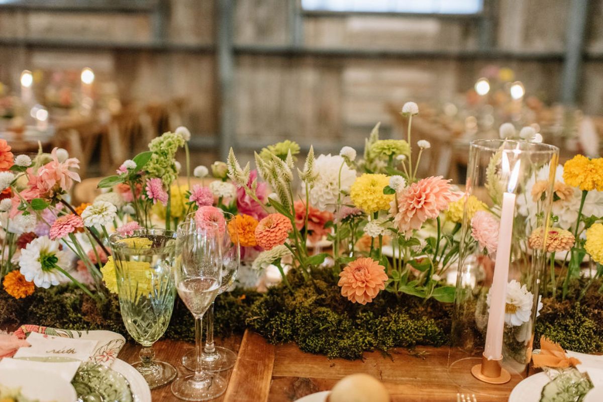 Moss table centerpiece runner with summer florals in sunset orange shades.