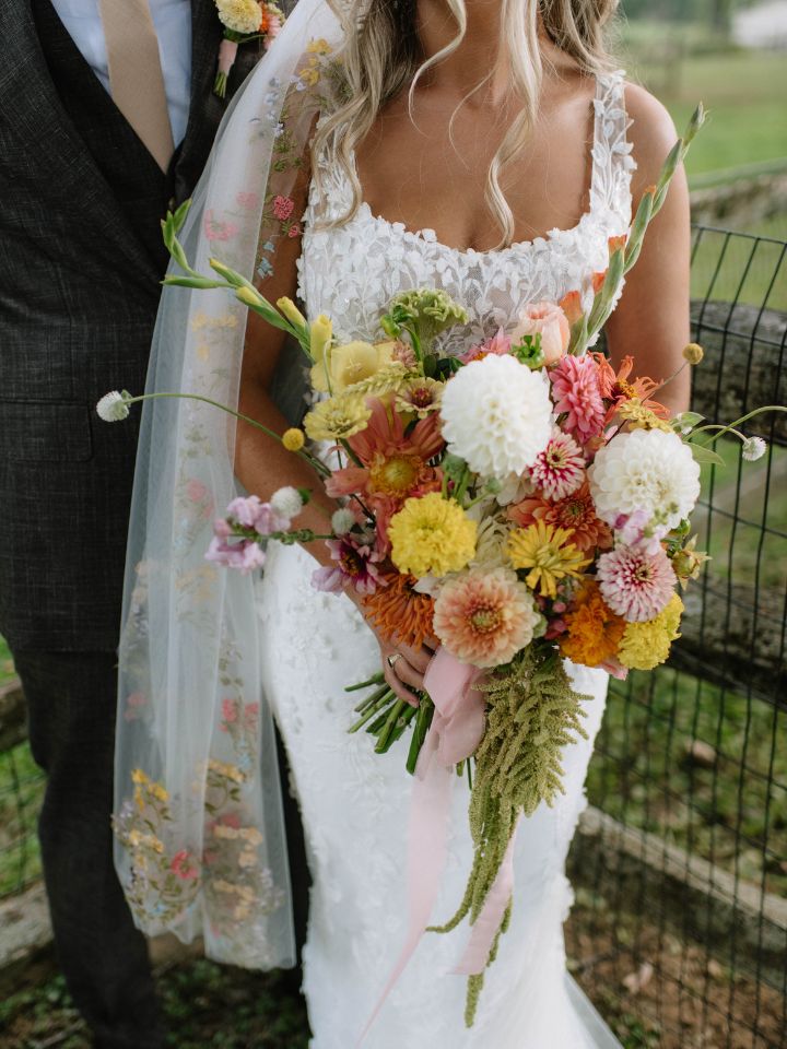 olivia classic organic Bride stands with groom, holding her bouquet of flower farm grown dahlias, marigolds, gladiolus, and amaranth.