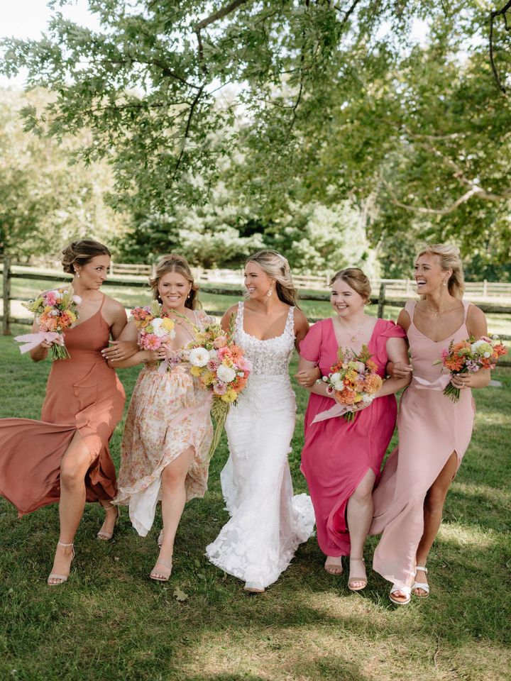 pink sunset bridesmaids Bride and bridesmaids walk carrying floral bouquets with dahlias.