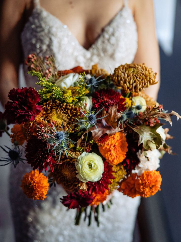 rounded classic regina Closeup of rich fall colors bridal bouquet held by bride.