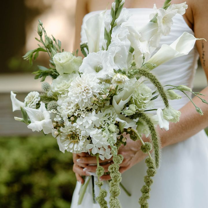 Bride holds white summer flower bridal bouquet.