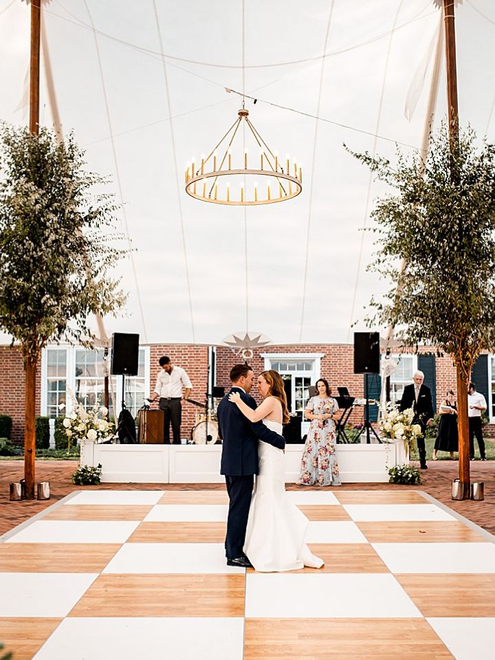 Couple dance under greenery installation in wedding reception tent at Brittland Estates.