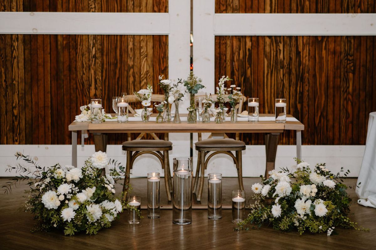 Sweetheart table at Kent Island Resort Farmstead with tall candles, and white flower arrangements.