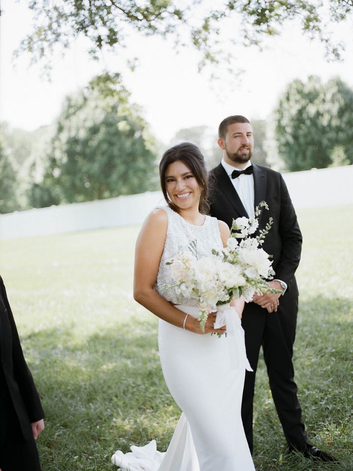 Bride smiles at camera, holding her bouquet.