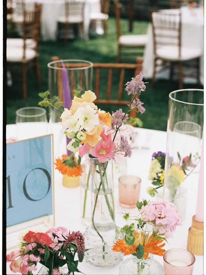 Colorful bud vases on guest table at wedding reception.