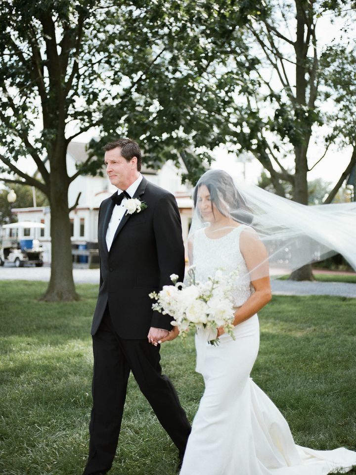 Bride and groom walk through grass.