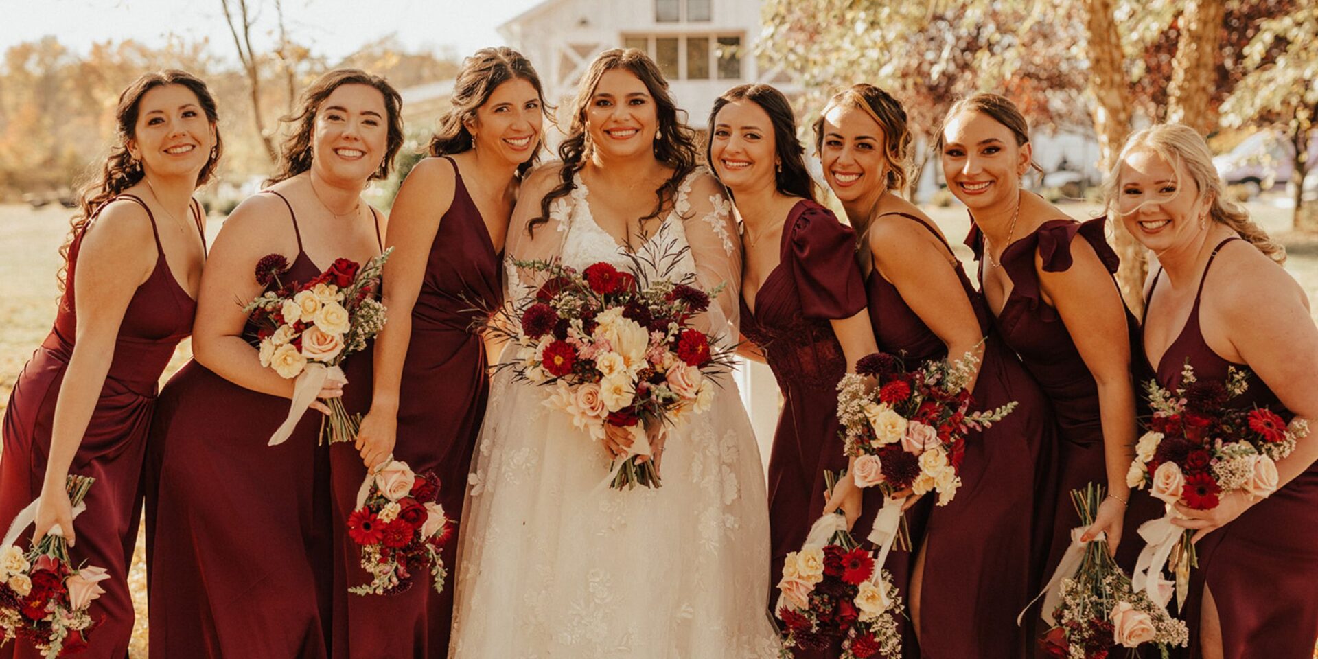 Bride and bridesmaids hold their burgundy and blush wedding bouquets.