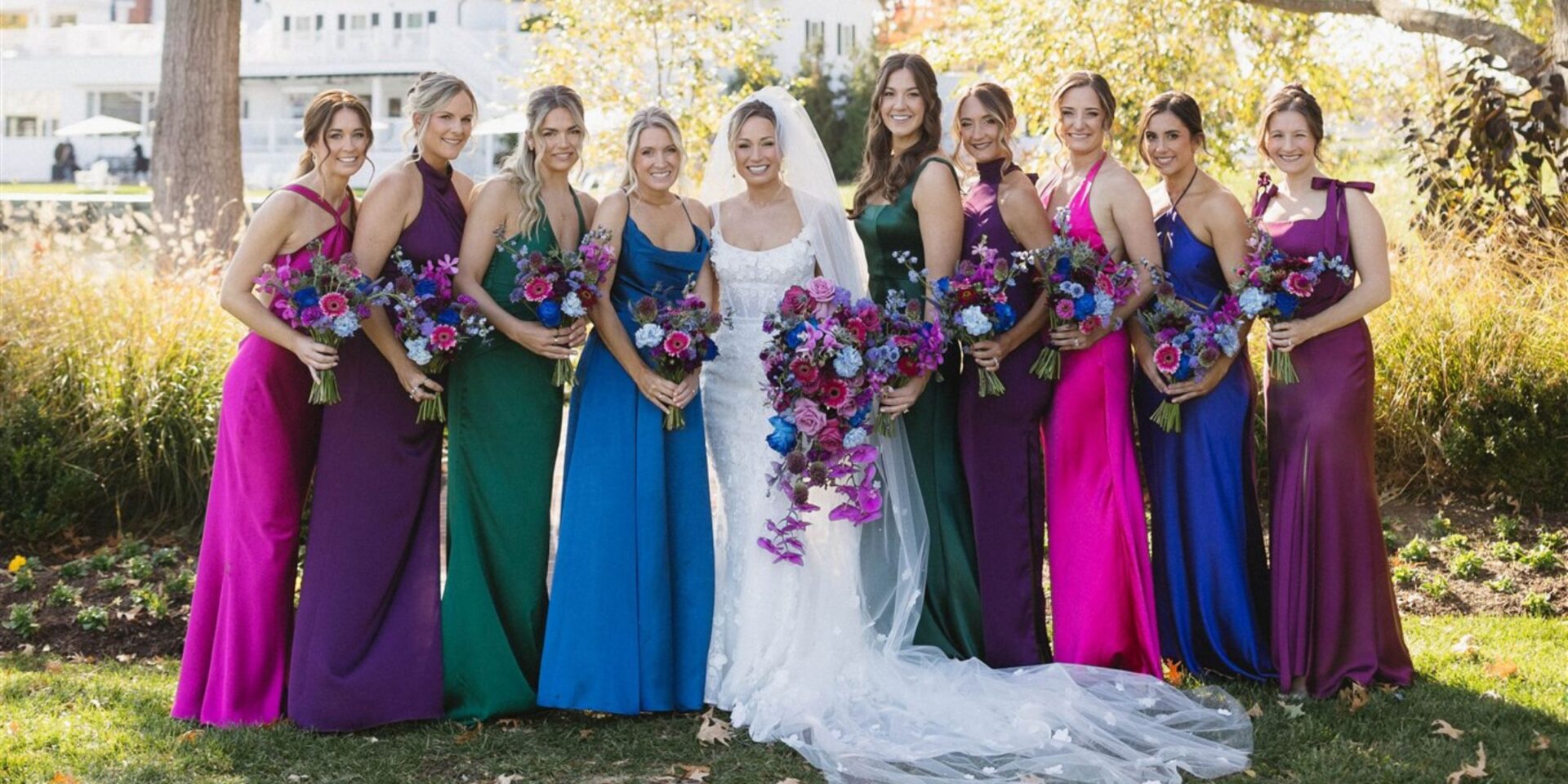 Bride and bridesmaids in bright fall jewel tone dresses.