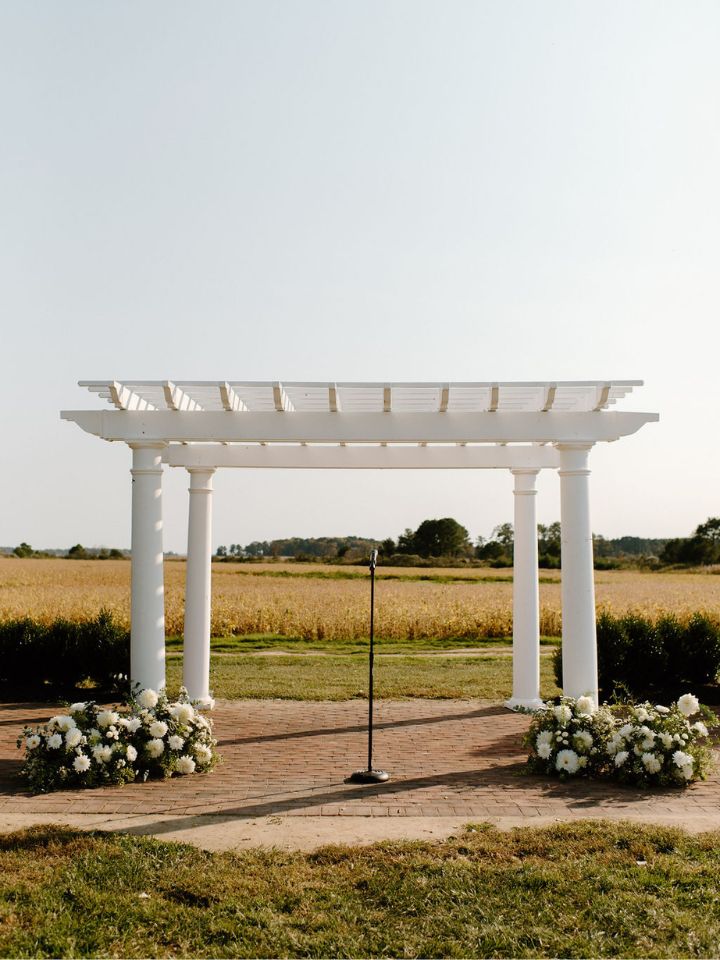 White pergola at Kent Island Resort with flower arrangements at base.