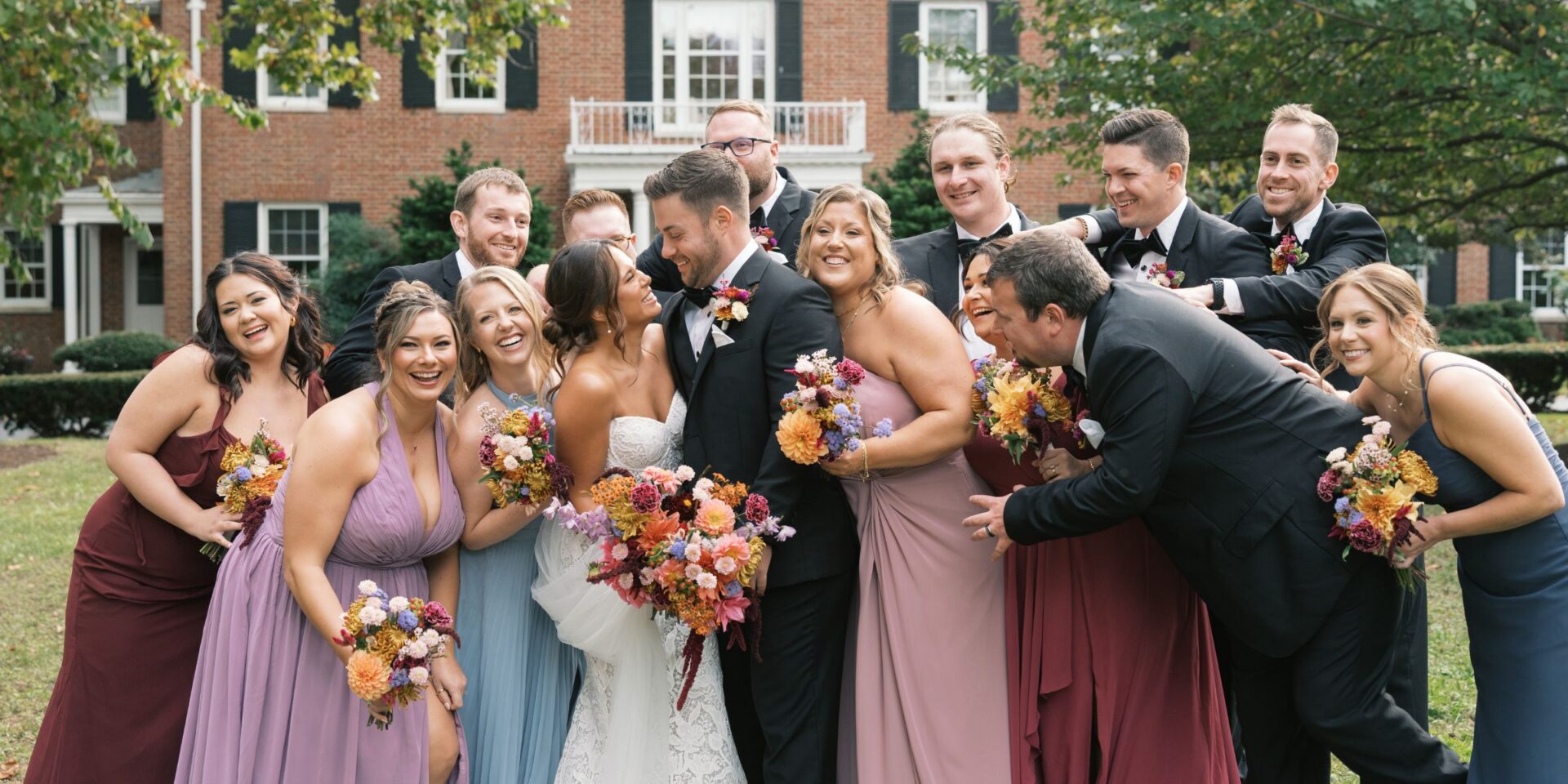 Bride and groom stand at center of cheering wedding party.