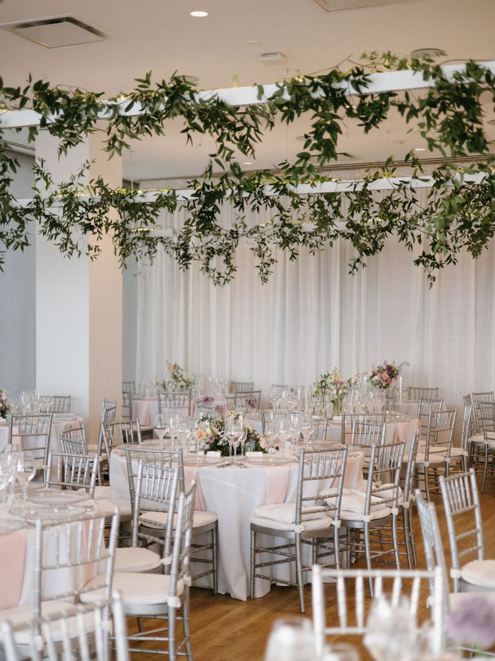 Indoor wedding reception with greenery installation in ceiling.