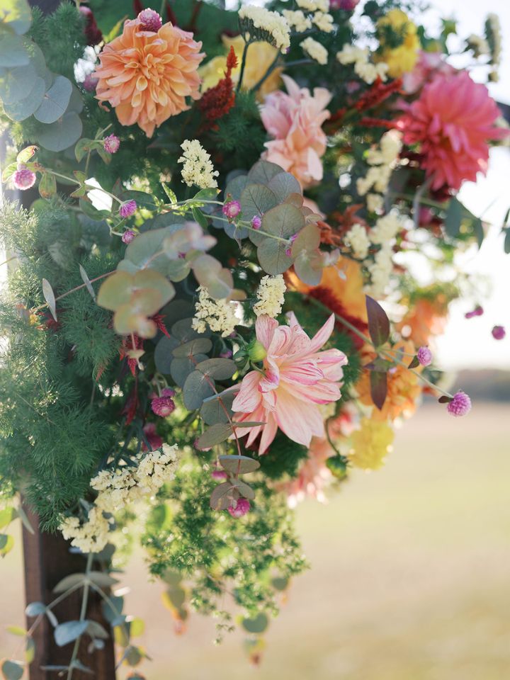 Closeup of fall wedding flowers on a ceremony arch.