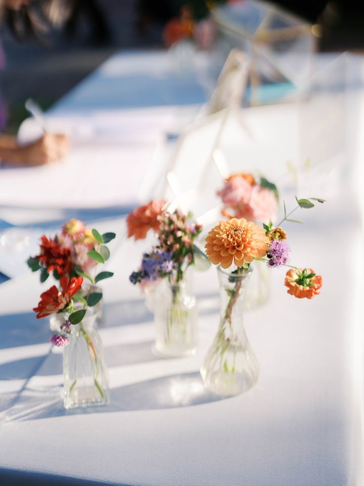 Bud vases with flowers on a white table linen.