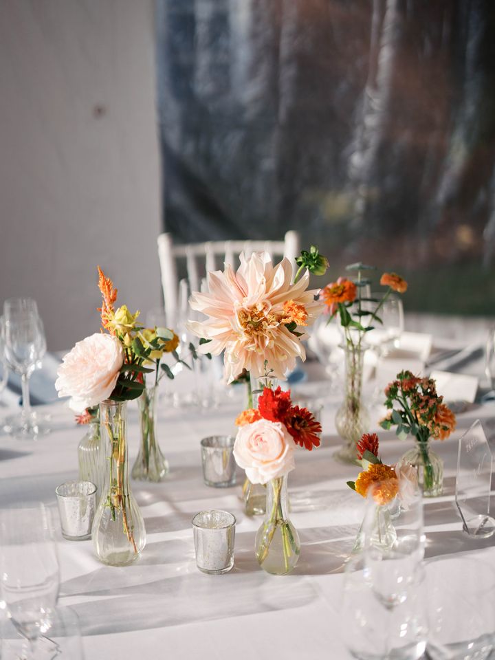 Bud vases with fall flowers on a wedding reception guest table.