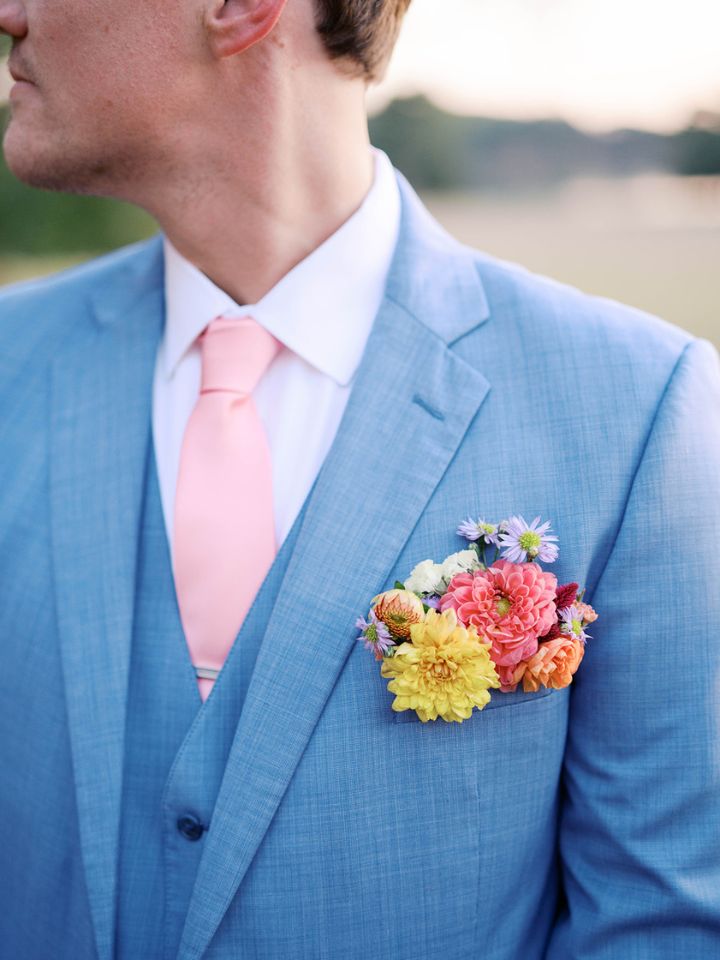 Closeup of flower pocket square boutonniere on a light blue suit.