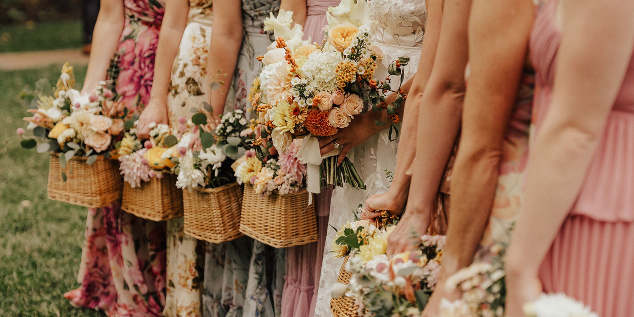Bridesmaids in shades of soft pink carry basket style bouquet arrangements.