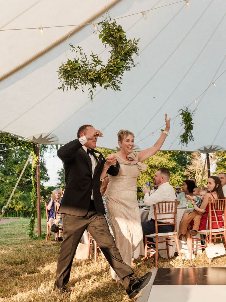 Guests walk into tent underneath greenery installation.