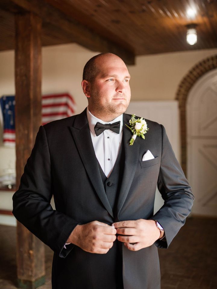 Groom in black tux with a white flower boutonniere.