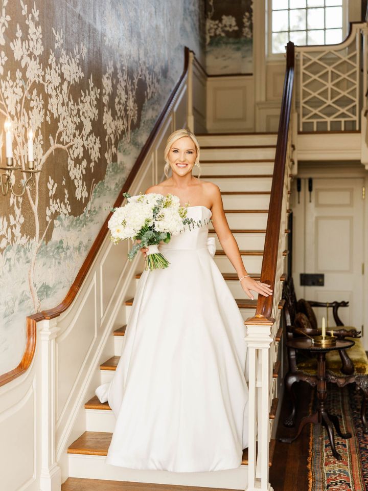 Bride walks down staircase inside Mount Harmon Plantation.