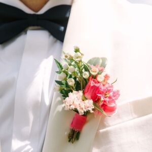 Pink floral boutonniere on a white dinner jacket.