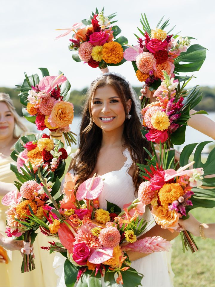 Bride smiles while bridesmaids hold their bouquets up to frame her face.