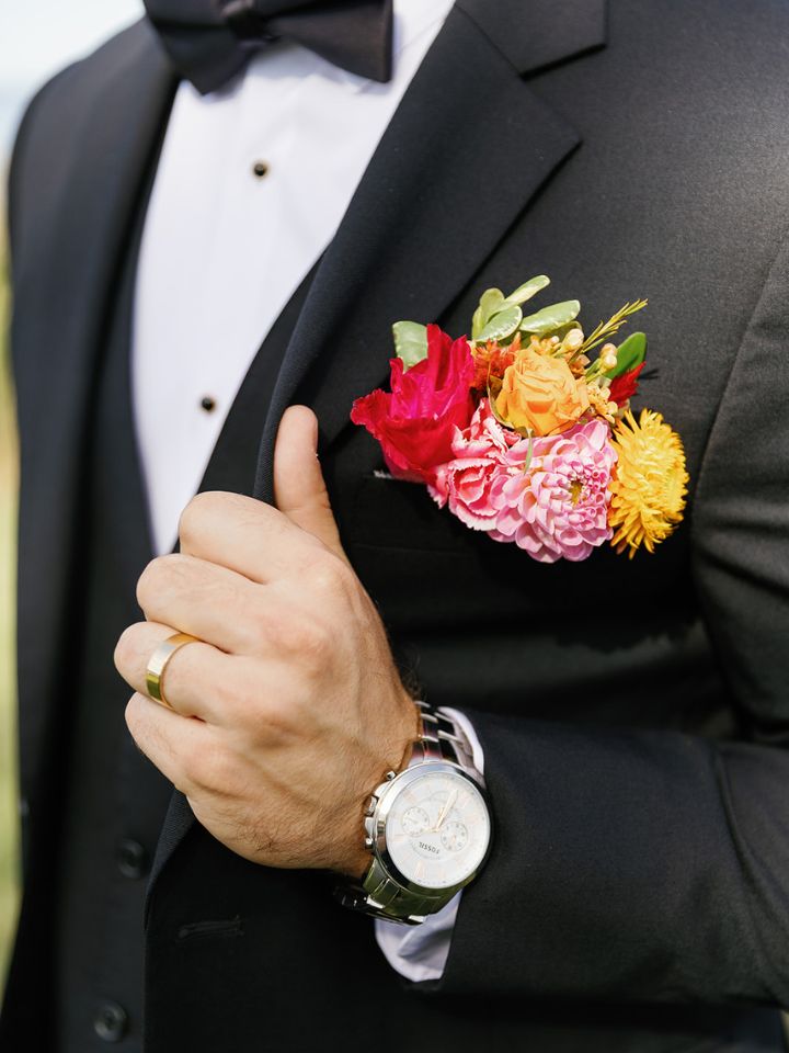 Closeup of groom's jacket with tropical flower inspired fresh flower pocket square style boutonniere.