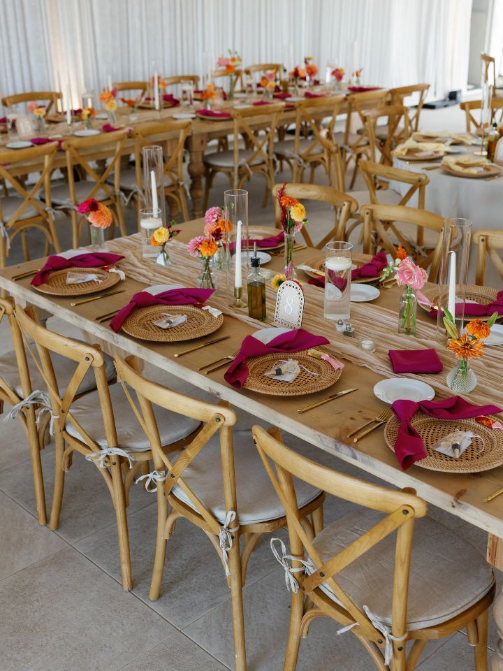 Rectangular wedding reception guest tables with bud vase flowers.