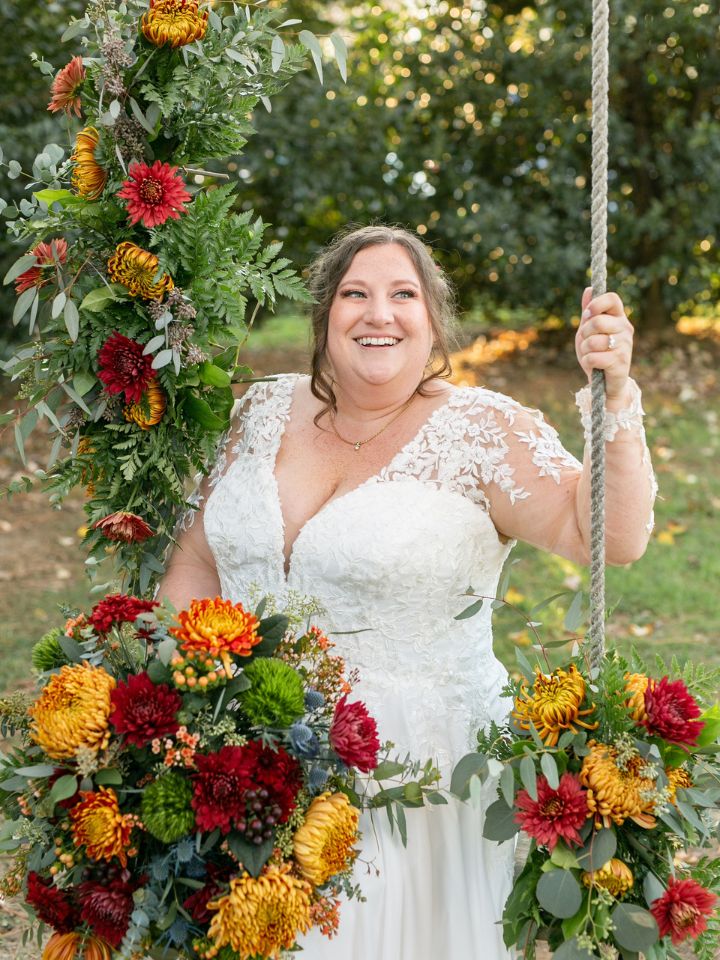 Wydler Swing Flowers Woman sits on swing with her fall bridal bouquet, and flowers on the swing as well.