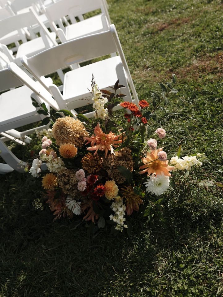 Warm Fall Color Wedding flowers sit at entrance to aisle.