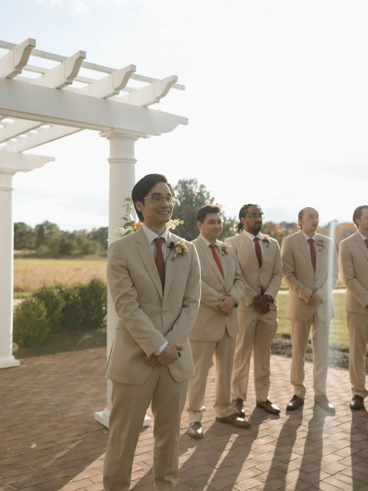 Groom and groomsmen in tan suits wait for wedding ceremony.
