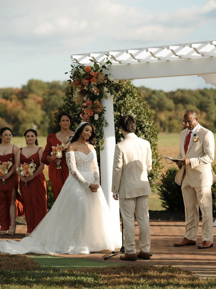 Bride and groom stand under Kent Island Resort pergola for wedding ceremony.