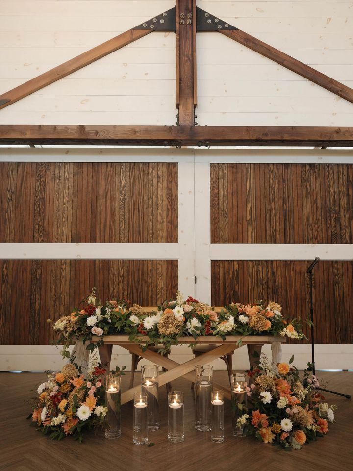 Sweetheart table with lots of fall flowers and candles.