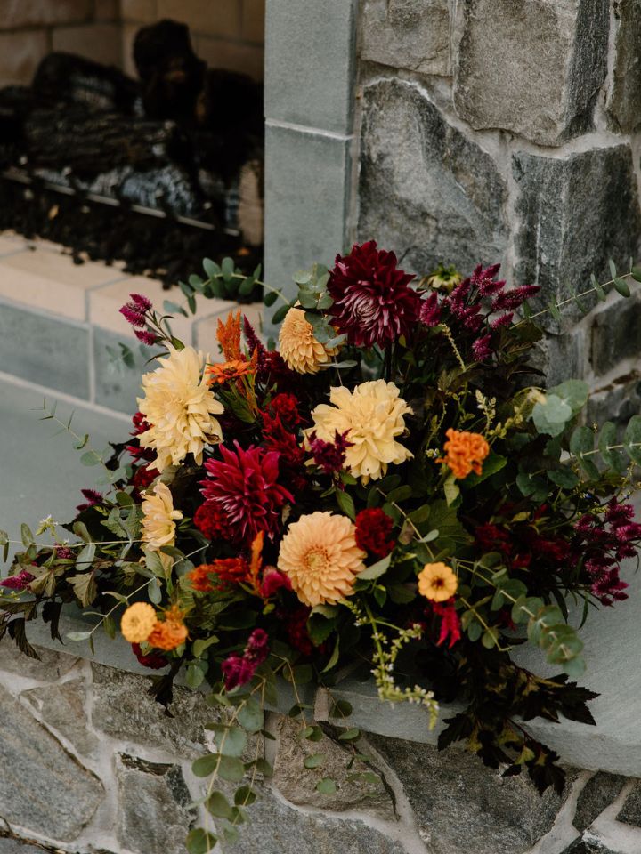 Fall flower arrangement sits on hearth of outdoor stone fireplace at Vanderwende Acres.