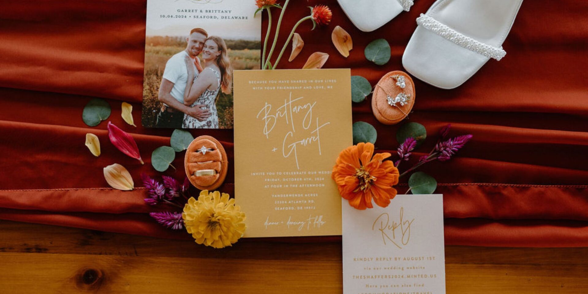 Flat lay photo with wedding invitation, rings, flowers.
