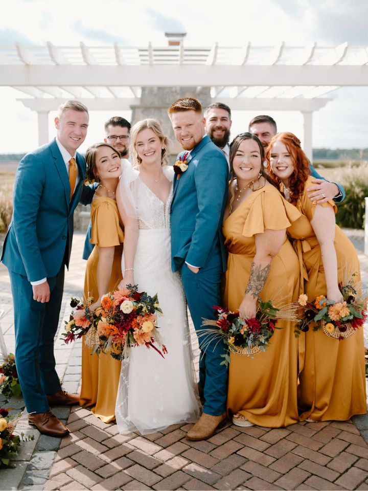 Bride and groom stand with wedding party, all holding their bouquets.
