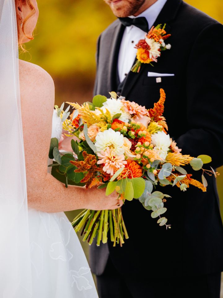 Closeup of bridal bouquet held between bride and groom.