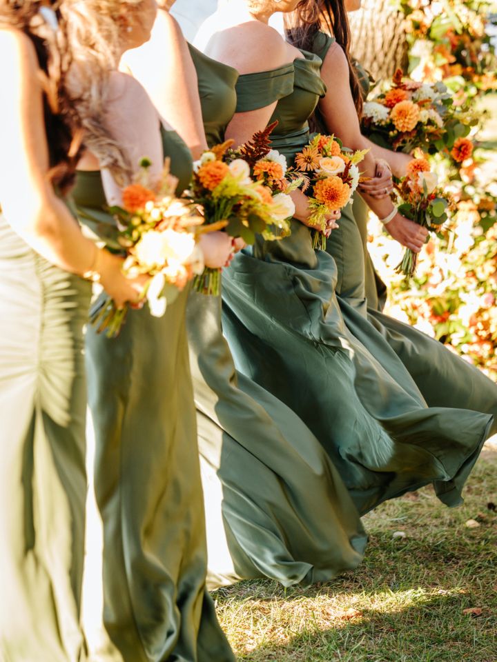 Olive green bridesmaid dresses lined up at ceremony with fall flower bouquets.