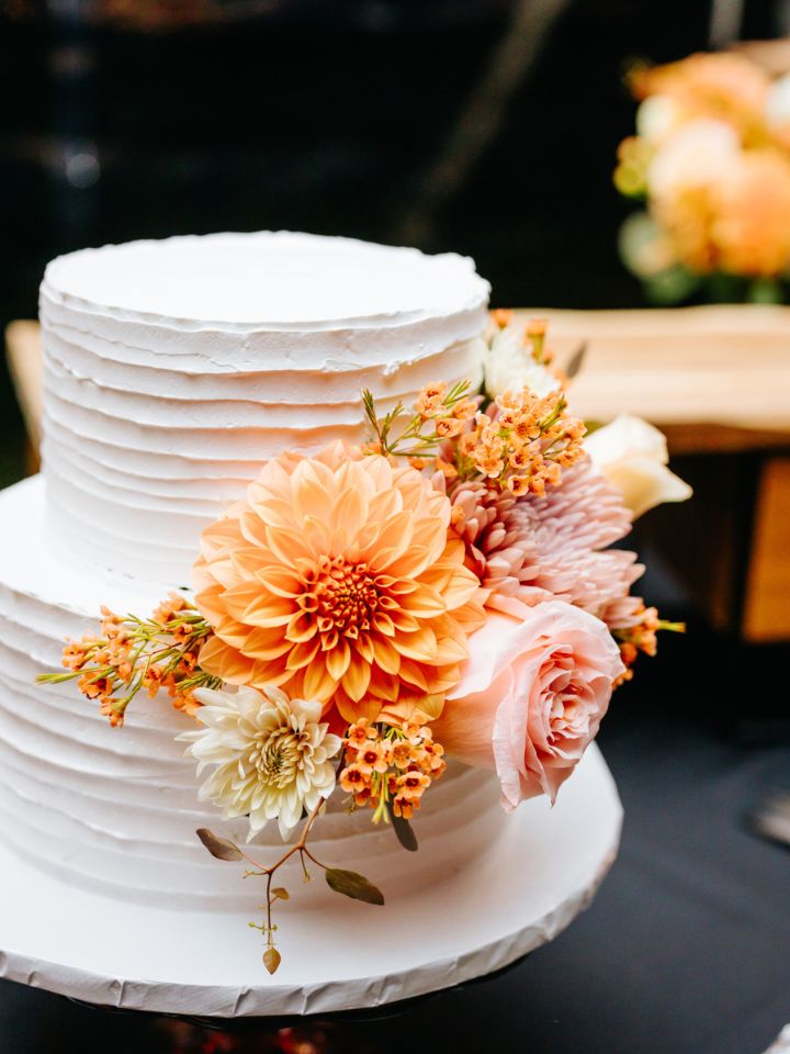 Two tier white wedding cake with textured icing and fall color flowers.