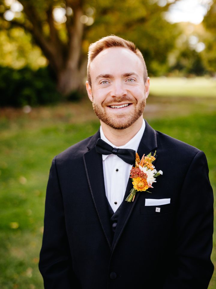 Groom poses in black tux with boutonniere.