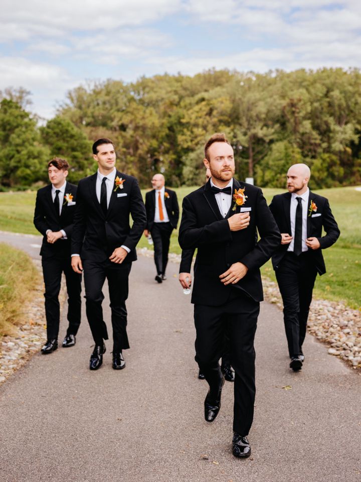 Groom and groomsmen in black tuxedos and fall flower boutonnieres.