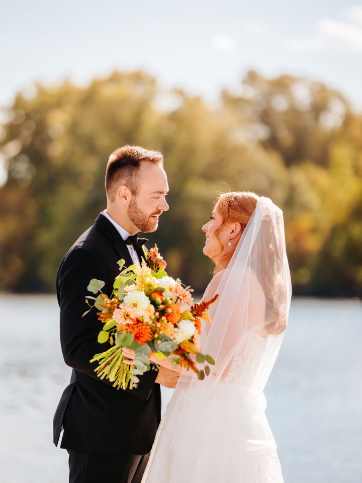 Bride and groom pose next to waterfront.