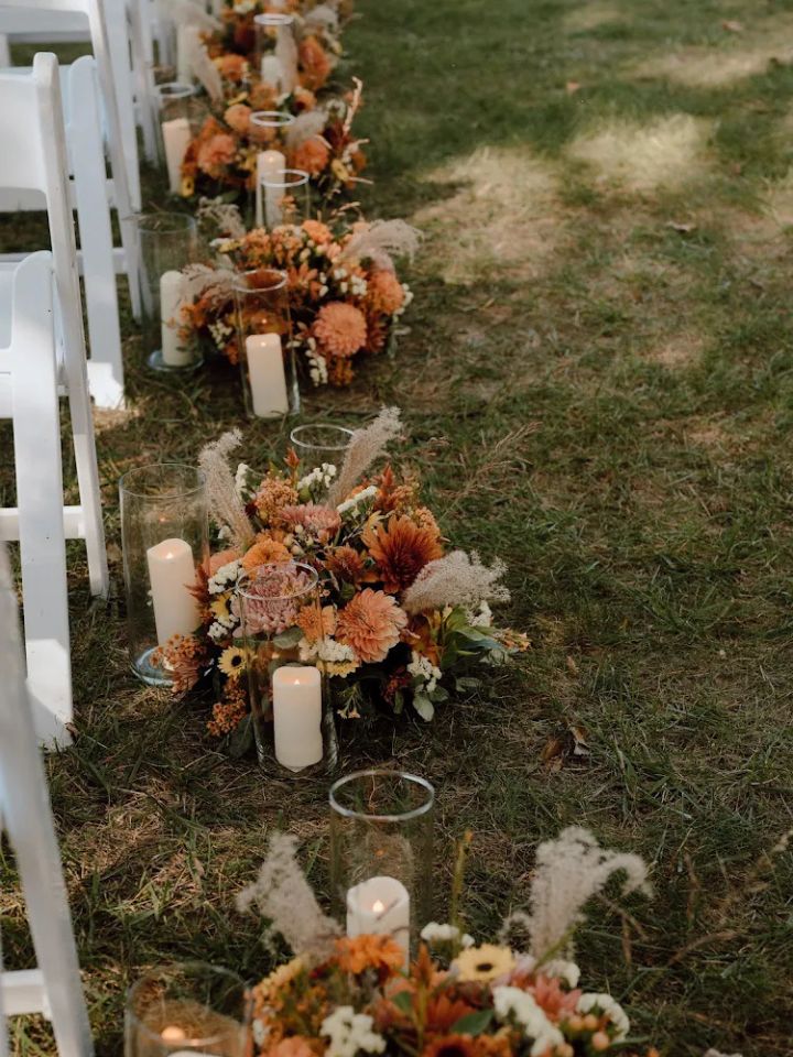 fall aisle flowers Flower centerpieces line the wedding ceremony aisle with candles, made with autumn colors.