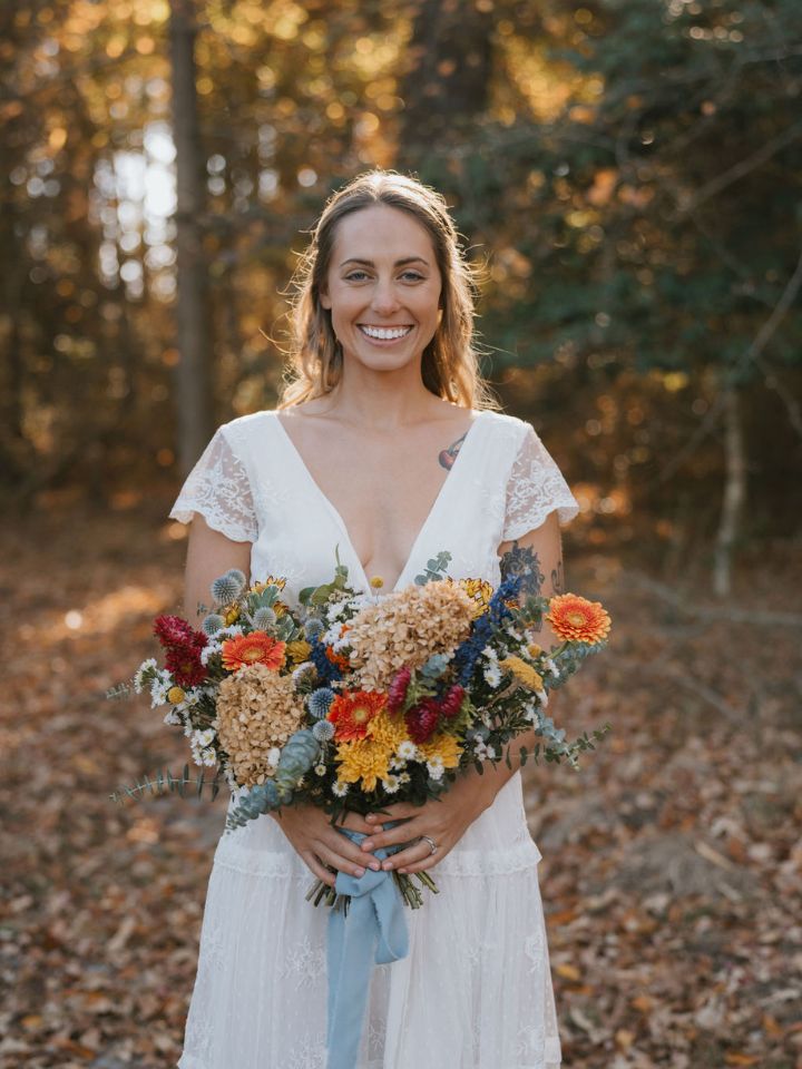 Bride poses with her bridal bouquet of fresh and dried flowers.