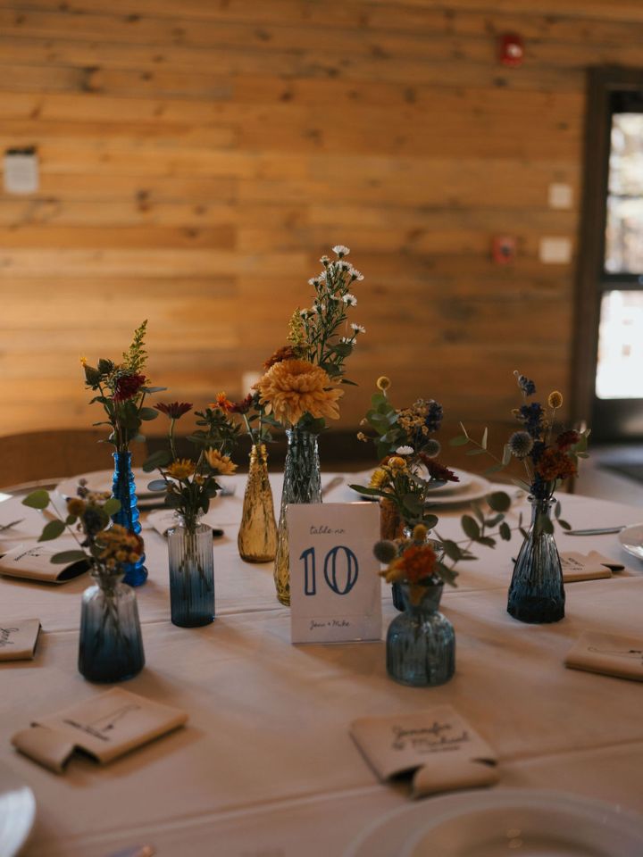 Table centerpiece for wedding with bud vases with fresh and dried flowers.