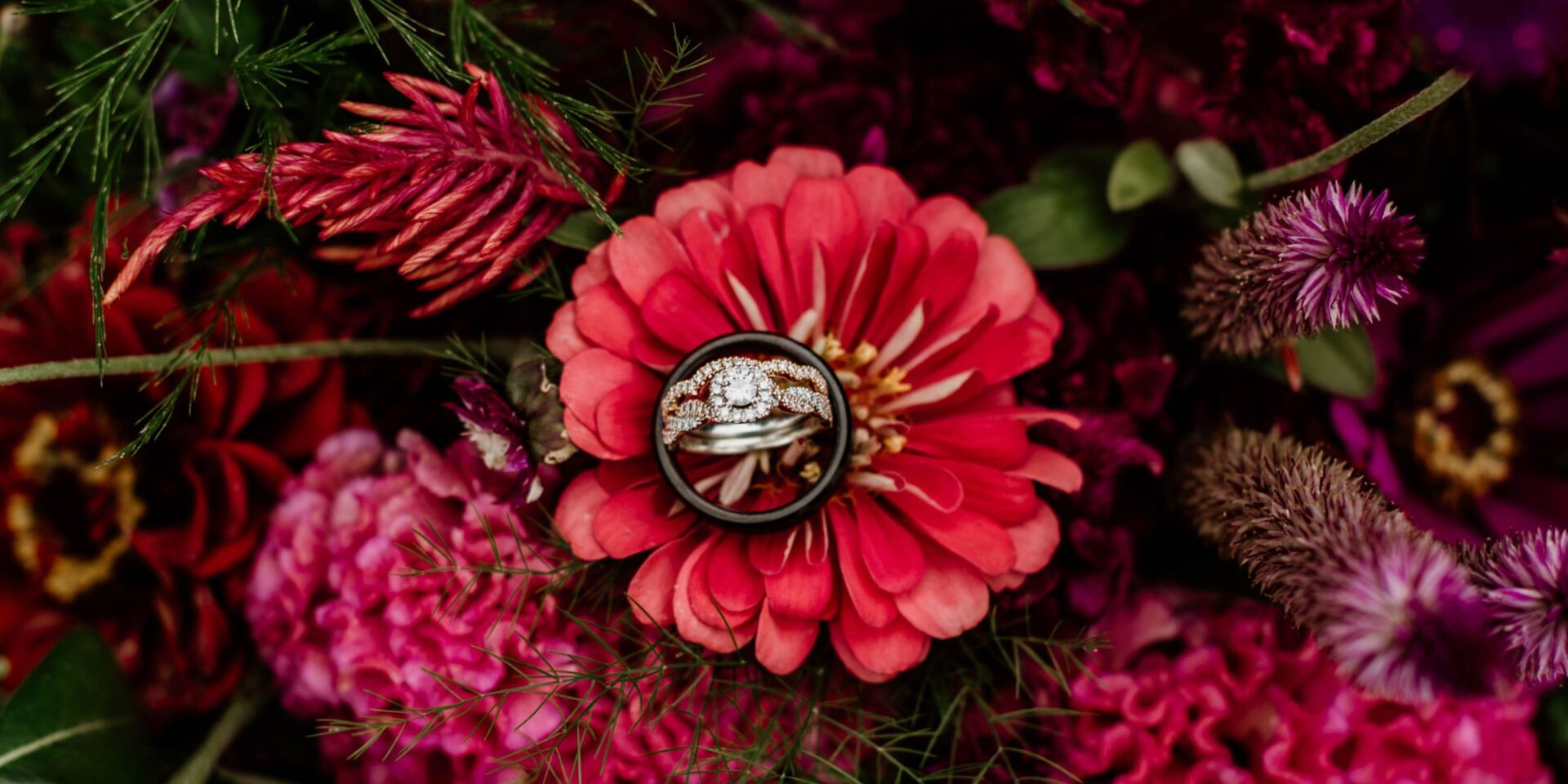 Detail photo of jewel tone summer flowers with wedding rings.