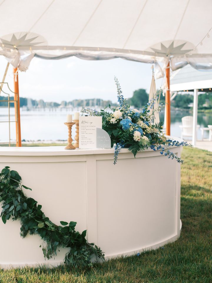 Round white bar with greenery and flower arrangement.