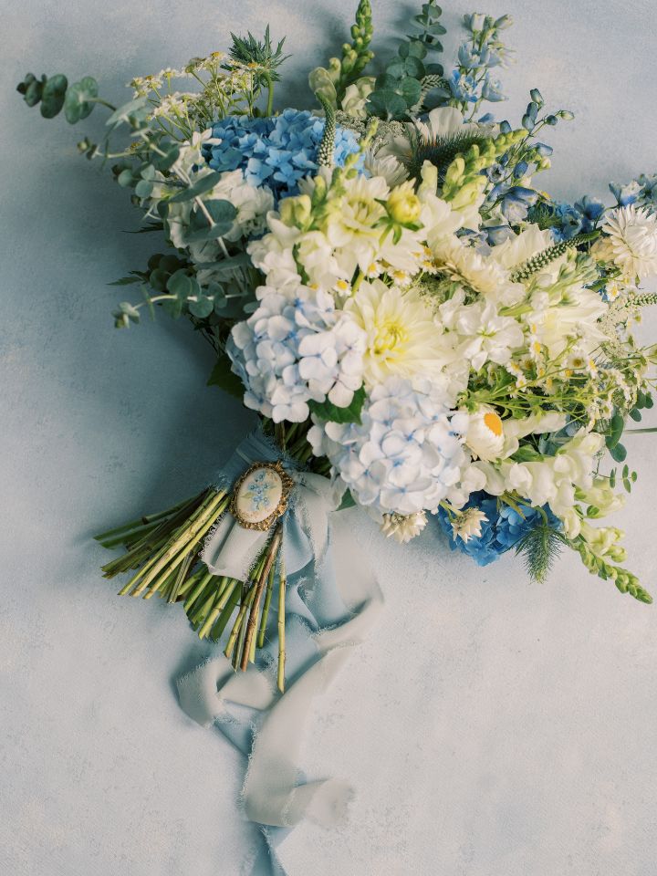 Photo of bridal bouquet laying flat, with ribbon wrap and charm.