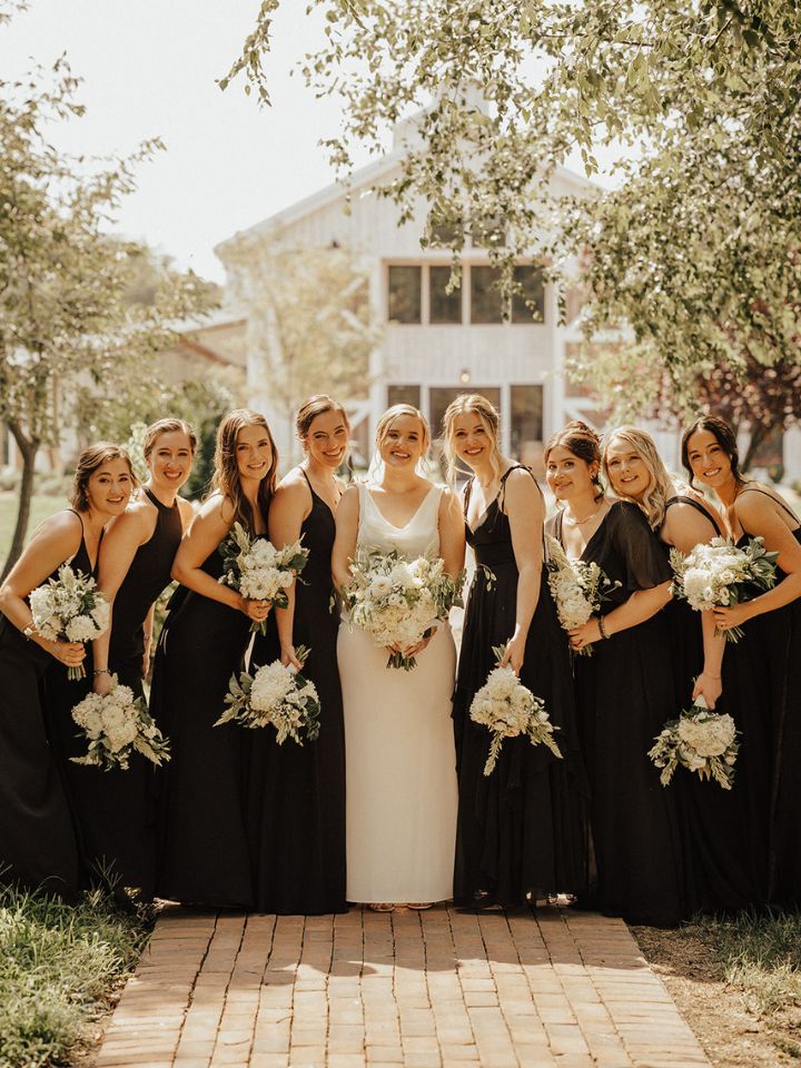 Black bridesmaid dresses with white flower bouquets.